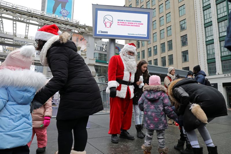 &copy; Reuters. A mask-less Santa Claus poses with children from an unmasked group protesting against coronavirus disease (COVID-19) restrictions in Toronto