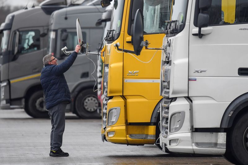 &copy; Reuters. A Hungarian truck driver adjusts a satellite dish for viewing television on the front of his lorry whilst he waits at Ashford International Truck Stop, in Ashford