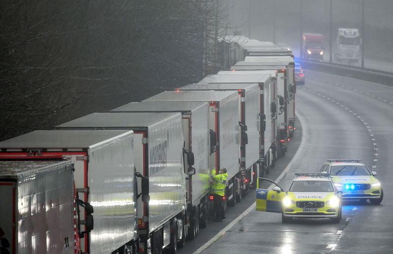 © Reuters. FILE PHOTO: Police officers speak to a driver in one of lorries parked on the M20 motorway towards Eurotunnel and the Port of Dover