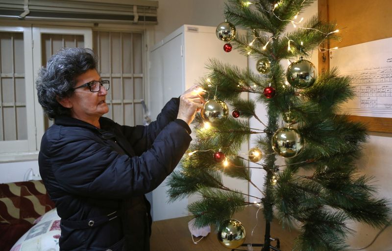 &copy; Reuters. Georgette Suleiman, 63, who looks after a Beirut school damaged by the Beirut port blast decorates a Christmas tree in Beirut