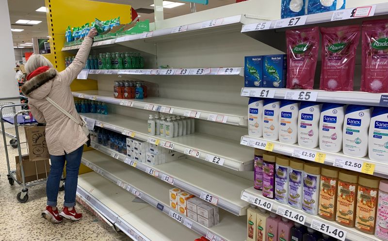 &copy; Reuters. Una cliente si alza sulle punte per prendere del sapone mani all&apos;interno di un supermercato Tesco a Manchester