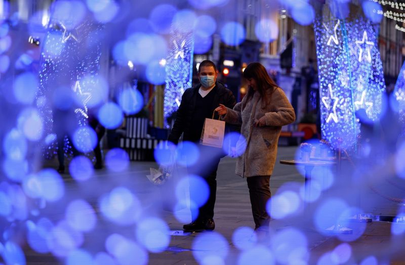 &copy; Reuters. Casal de máscara caminha em rua de Londres em meio a luzes do Natal