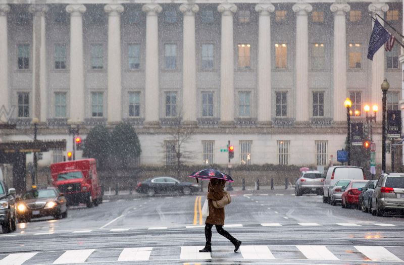 &copy; Reuters. A woman crosses a nearly empty street at rush hour, near the U.S. Treasury Building during a snow storm in Washington