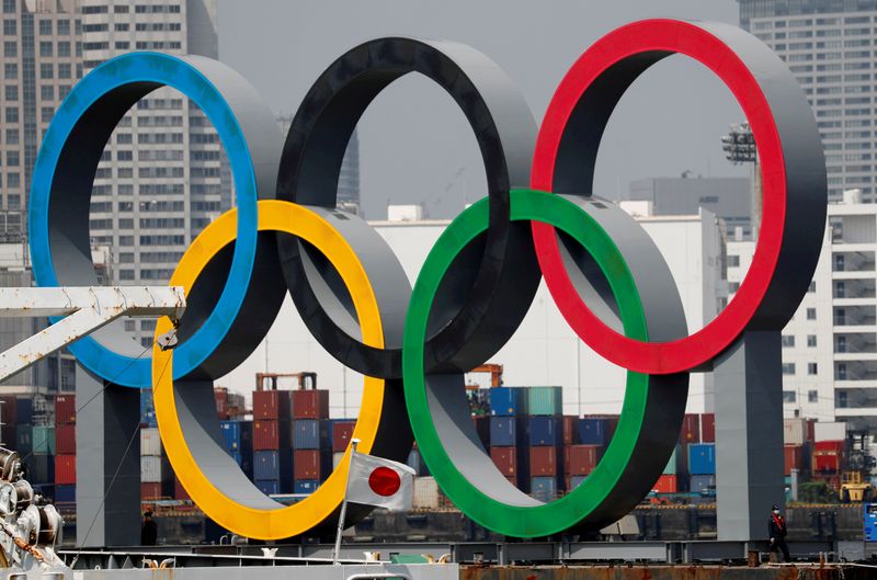 &copy; Reuters. FILE PHOTO: The giant Olympic rings are seen behind Japan&apos;s national flag at the waterfront area at Odaiba Marine Park in Tokyo
