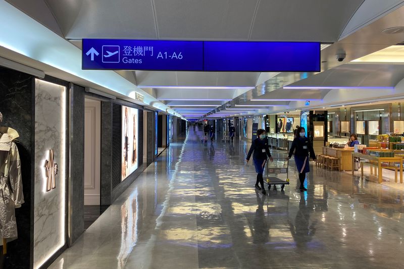 &copy; Reuters. FILE PHOTO: Staff wearing masks to prevent the spread of the coronavirus disease (COVID-19), walk past shops at the Taipei’s Taoyuan International Airport, in Taiwan