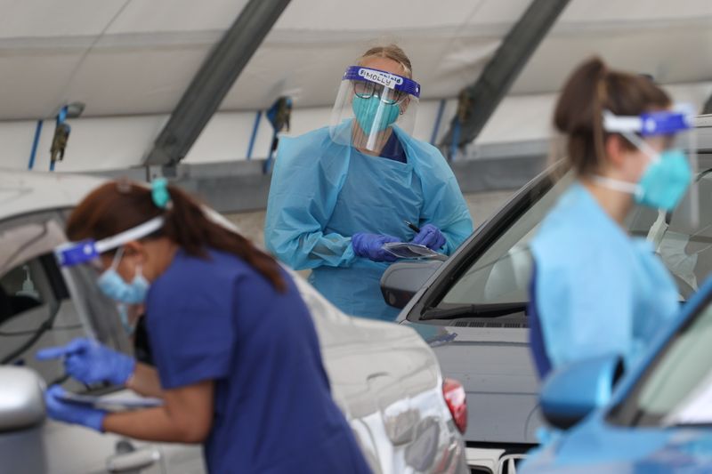 &copy; Reuters. FILE PHOTO: Medical workers administer tests at a drive-through COVID-19 testing centre in Sydney