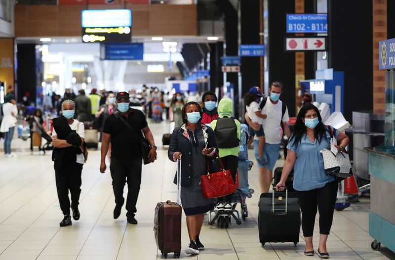 &copy; Reuters. FILE PHOTO:  Passengers wearing protective masks walk to the check-in counters at the O.R. Tambo International Airport in Johannesburg
