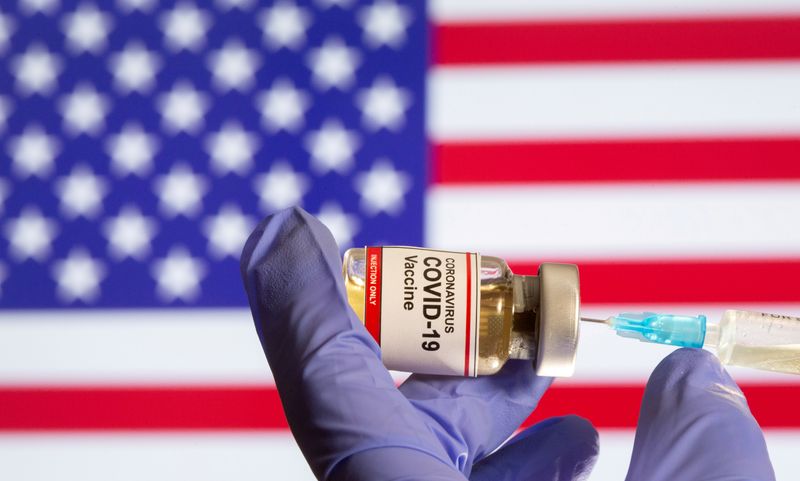 &copy; Reuters. FILE PHOTO: A small bottle labeled with a &quot;Coronavirus COVID-19 Vaccine&quot; sticker and a medical syringe in front of displayed USA flag in this illustration