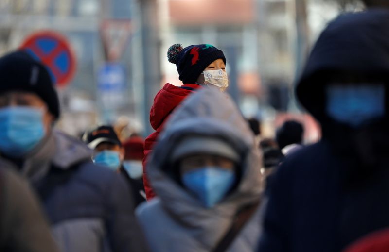 &copy; Reuters. FILE PHOTO: People wearing masks walk in a street in Beijing&apos;s CBD during morning rush hour