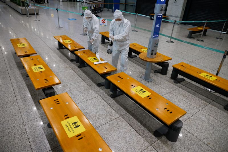 &copy; Reuters. Trabalhadores em trajes de proteção desinfetam área de desembarque do aeroporto de Incheon, na Coreia do Sul