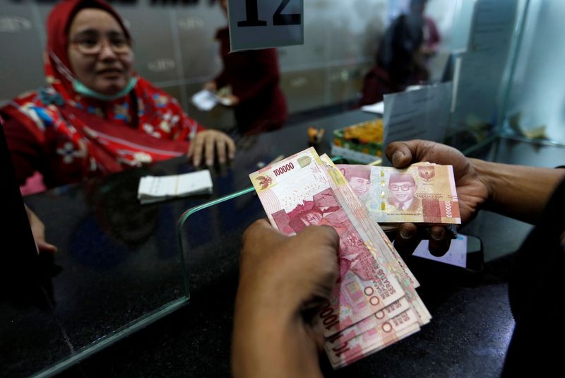 &copy; Reuters. FILE PHOTO: A customer holds Indonesian rupiah bank notes at a money changer in Jakarta, Indonesia