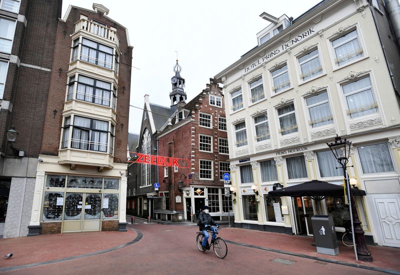 &copy; Reuters. Homem usando máscara anda de bicicleta em rua vazia de Amsterdã durante pandemia de Covid-19