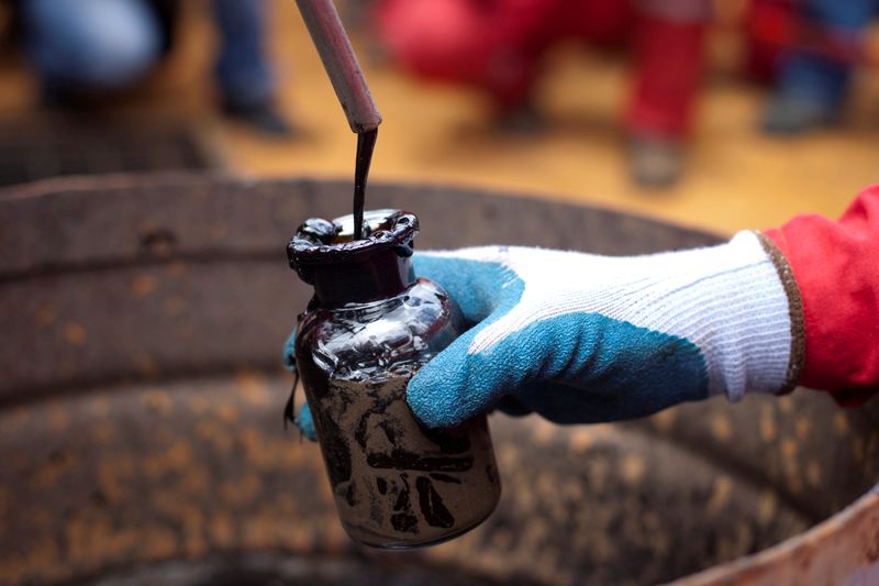 © Reuters. FILE PHOTO: A worker collects a crude oil sample at an oil well operated by Venezuela's state oil company PDVSA in Morichal