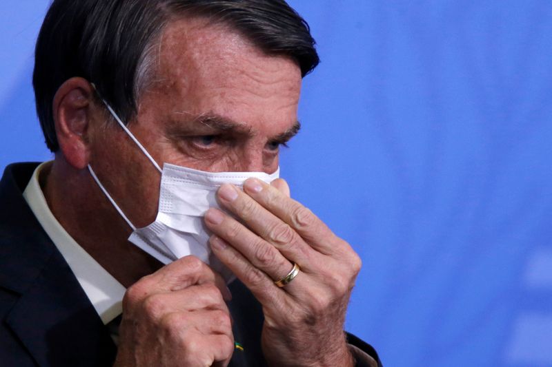 &copy; Reuters. FILE PHOTO: Brazil&apos;s President Jair Bolsonaro looks on as he adjusts his protective face mask during a ceremony launching a program to expand access to credit at the Planalto Palace in Brasilia