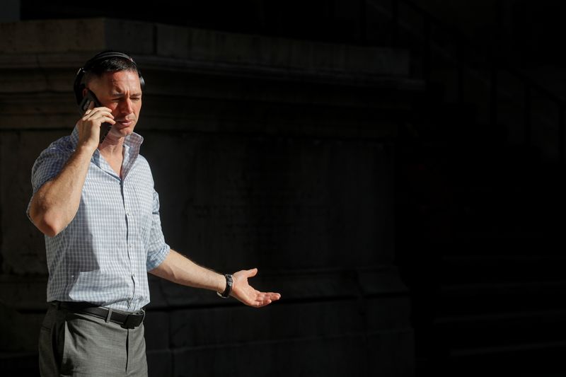 &copy; Reuters. A man uses his phone on Wall St. outside the NYSE in New York