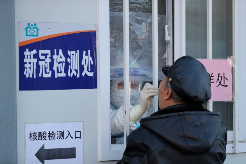 &copy; Reuters. FILE PHOTO: Medical worker collects a swab from a man for nucleic acid testing at a hospital in Shenyang