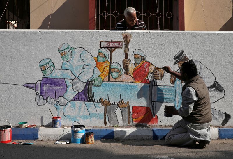 © Reuters. Man applies finishing touches to graffiti representing a vaccine in Kolkata