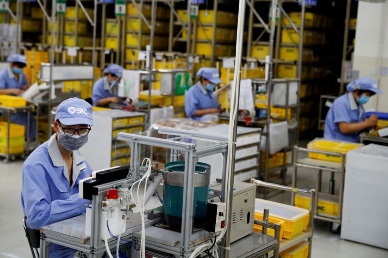 © Reuters. FILE PHOTO: Employees wearing face masks work at a factory of the component maker SMC during a government organised tour of its facility following the outbreak of the coronavirus disease (COVID-19), in Beijing