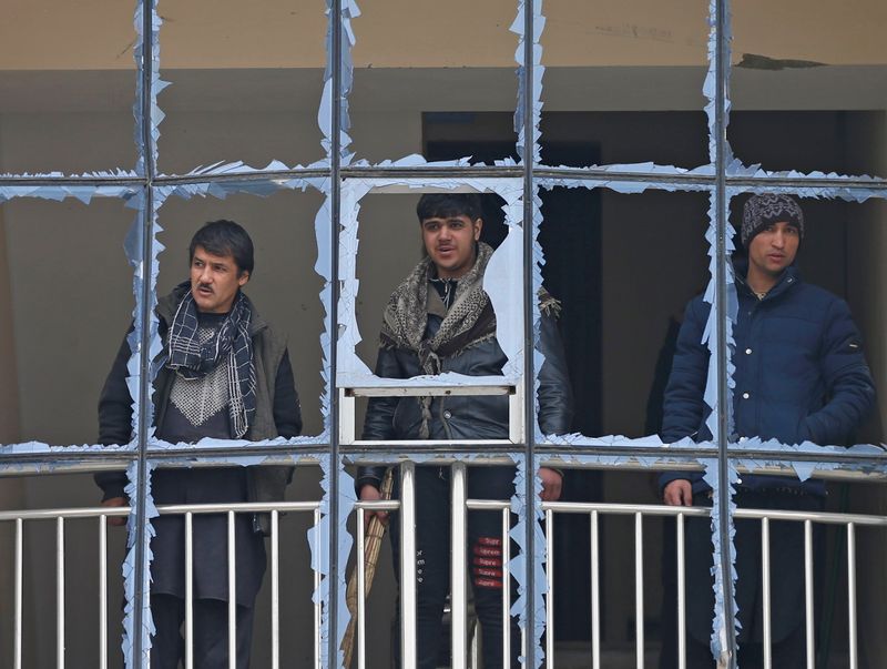 © Reuters. Afghan men look out from a damaged window of their building at the site of a blast in Kabul