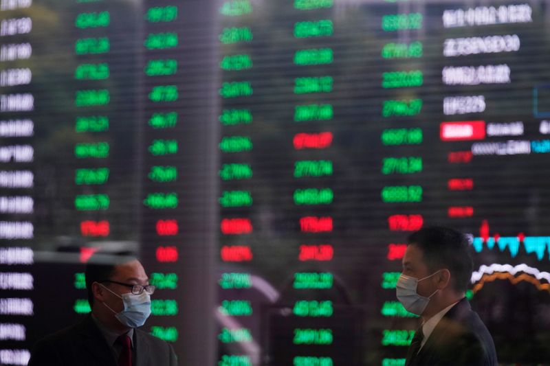 &copy; Reuters. Due uomini con mascherine all&apos;interno della Borsa di Shanghai, davanti a un tabellone elettronico