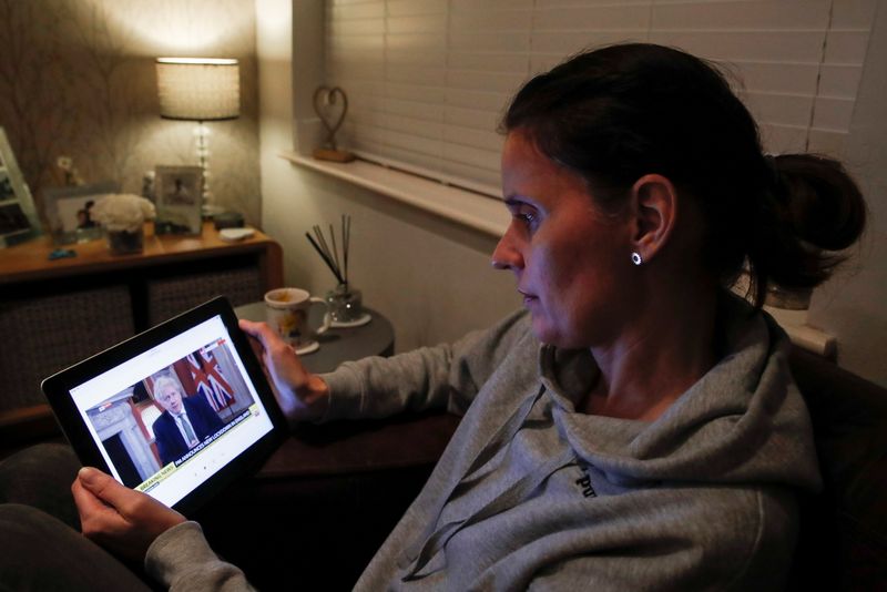 © Reuters. Teacher Wendy Couldridge watches on a device as Britain's Prime Minister Boris Johnson announces a lockdown in England