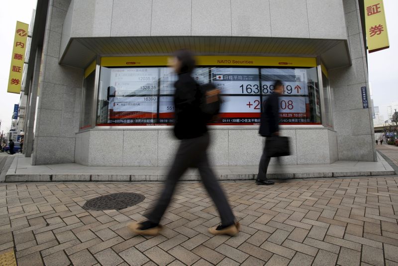 © Reuters. FILE PHOTO: Pedestrians walk pass an electronic board outside a brokerage in Tokyo