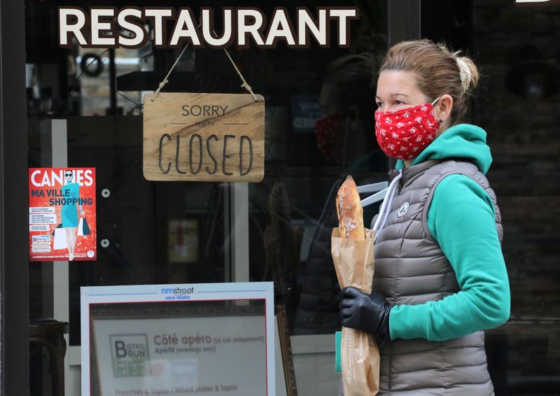 &copy; Reuters. FILE PHOTO: A woman wearing a protective face mask holds a French baguette in Cannes