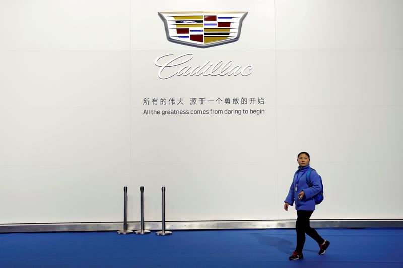 © Reuters. FILE PHOTO: Woman walks past a board with a sign of Cadillac of GM during the media day for Shanghai auto show