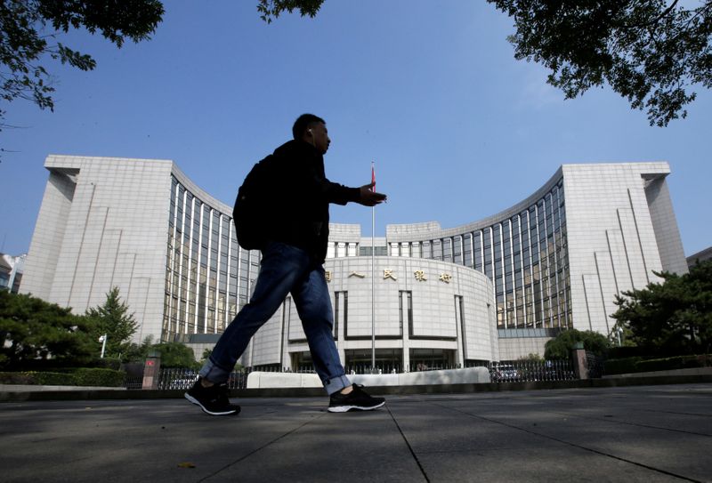 © Reuters. FILE PHOTO: A man walks past the headquarters of the PBOC, the central bank, in Beijing