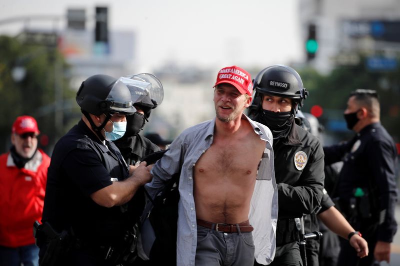 © Reuters. A supporter of U.S. President Donald Trump wearing a Make America Great Again (MAGA) hat reacts upon getting detained by the police while protesting in Los Angeles, California