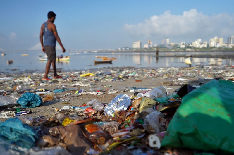 &copy; Reuters. FILE PHOTO: A man walks on a garbage-strewn beach in Mumbai