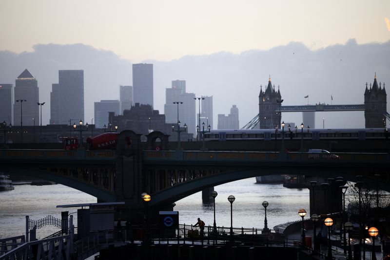 &copy; Reuters. Canary Wharf can be seen in the distance as a person walks along a footbridge, amid the coronavirus disease (COVID-19) outbreak, in London