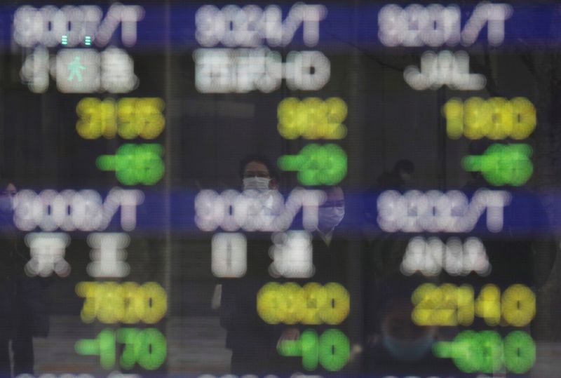 &copy; Reuters. Diversi passanti riflessi su uno schermo nel distretto finanziario di Tokyo, in Giappone