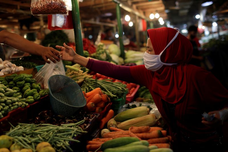&copy; Reuters. A woman wearing a protective mask shops for vegetables at a traditional market, as the coronavirus disease (COVID-19) outbreak continues, in Jakarta