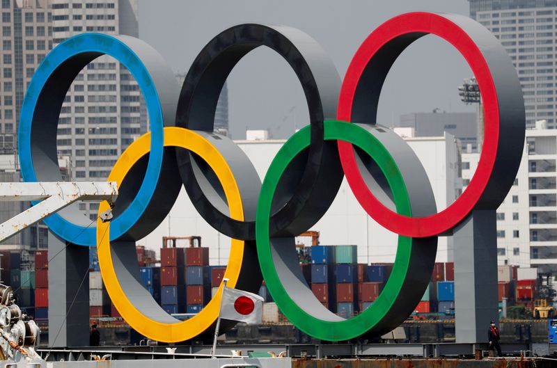 © Reuters. FILE PHOTO: The giant Olympic rings are seen behind Japan's national flag at the waterfront area at Odaiba Marine Park in Tokyo