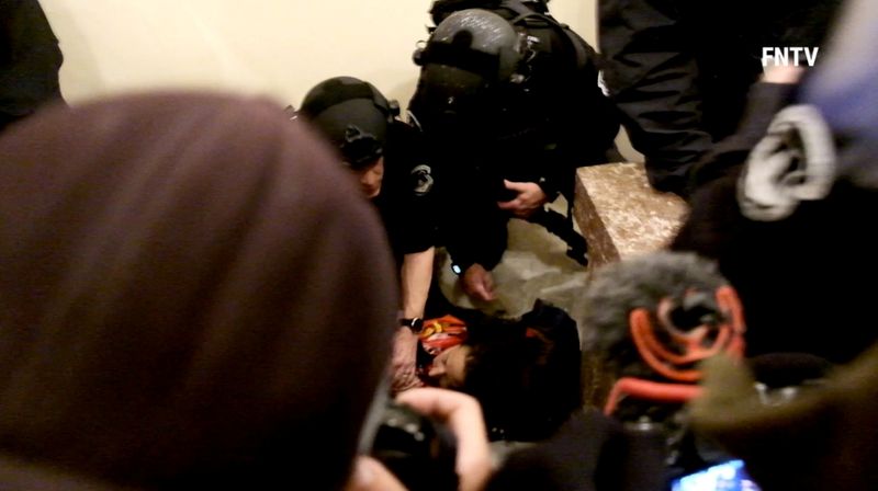 © Reuters. Police help a woman, who was shot, as she lies on the floor, after supporters of U.S. President Donald Trump entered the Capitol building in Washington DC, U.S. , in this still frame obtained from social media video