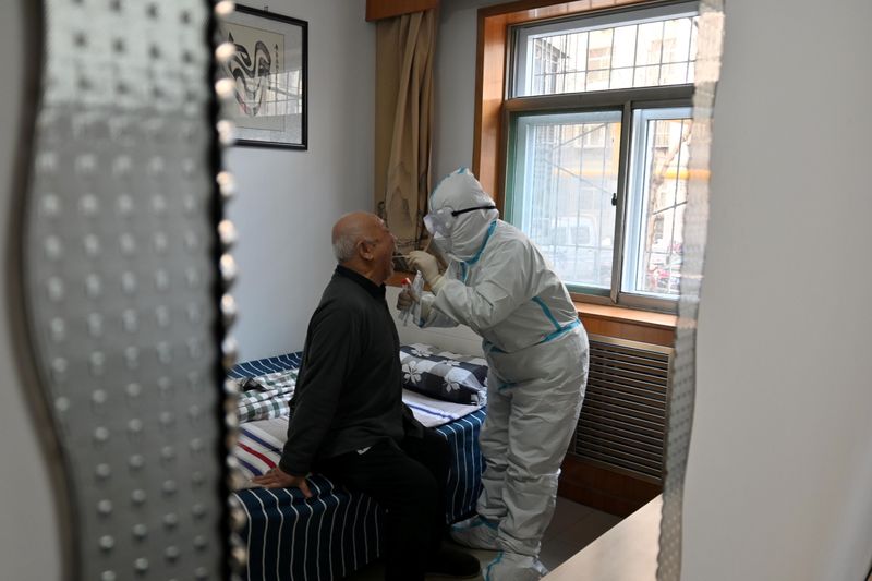 © Reuters. Medical worker in protective suit collects a swab from an elderly during a door-to-door nucleic acid sampling in Shijiazhuang