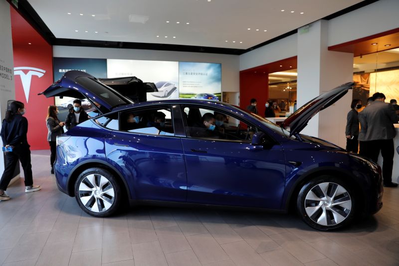 © Reuters. Visitors wearing face masks check a China-made Tesla Model Y sport utility vehicle (SUV) at the electric vehicle maker's showroom in Beijing