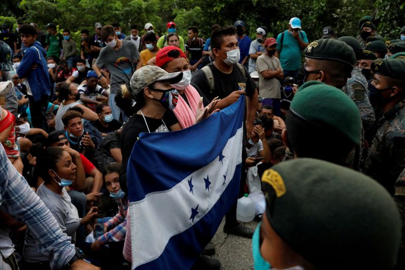 &copy; Reuters. FILE PHOTO: Honduran migrants trying to reach the U.S. hold a Honduran flag while standing in front of Guatemalan soldiers blocking a road to stop migrants from reach the Mexico&apos;s border, in San Pedro Cadenas