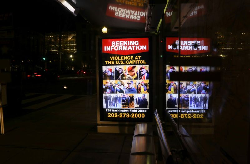 © Reuters. A sign at a bus stop shows people wanted by law enforcement, three days after a protest of the U.S. Congress certification of the November election results the 2020 election in Washington