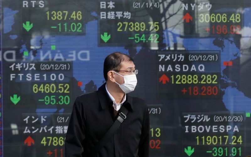 &copy; Reuters. Un uomo con una mascherina davanti a schermi con dati sugli indici di diverse importanti borse a Tokyo