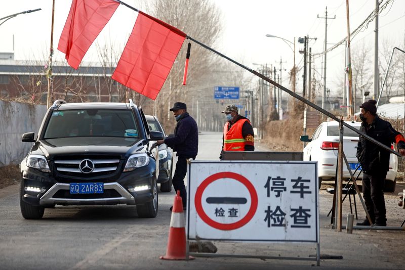 &copy; Reuters. Voluntários param carro em posto de controle em estrada que leva para o vilarejo onde moram nos arredores de Pequim