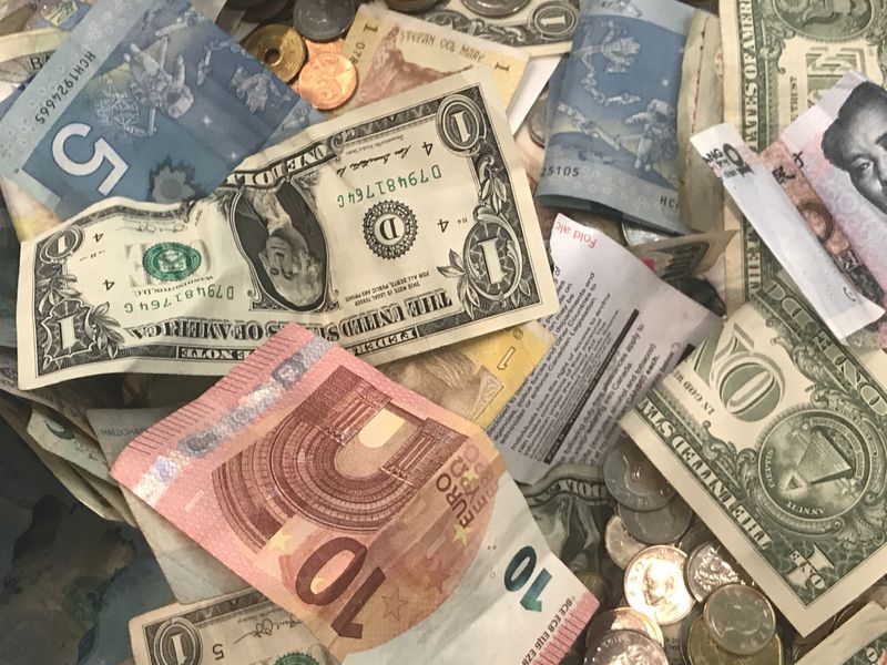 © Reuters. FILE PHOTO: U.S. dollars and other world currencies lie in a charity receptacle at Pearson international airport in Toronto