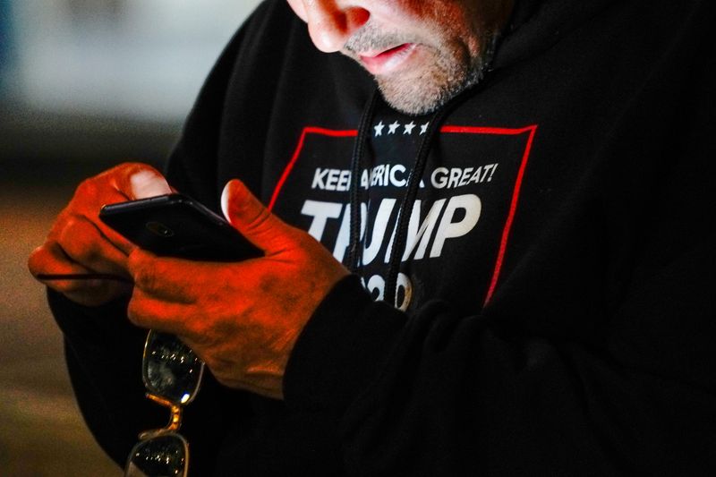 &copy; Reuters. FILE PHOTO: A man wearing a &quot;Trump 2020&quot; sweatshirt uses his mobile phone during a &quot;Stop the Steal&quot; protest outside Milwaukee Central Count the day after Milwaukee County finished counting absentee ballots, in Milwaukee