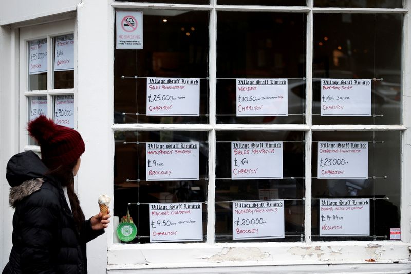 © Reuters. FILE PHOTO: A person looks at advertisements in the window of a job agency in London