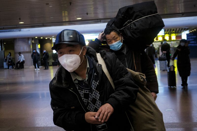 &copy; Reuters. Travellers walk with their belongings at a railway station in Beijing