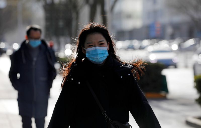 &copy; Reuters. Foto del lunes de una mujer caminando con una mascarilla en Pekín