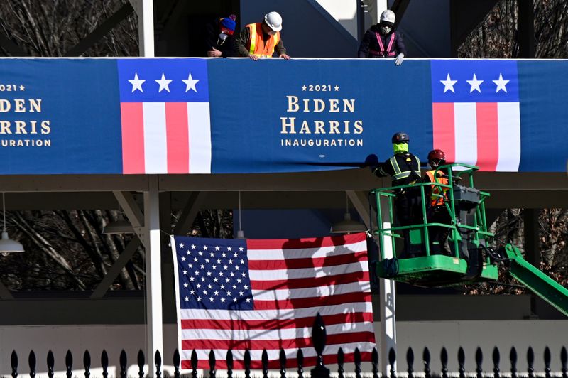 &copy; Reuters. FILE PHOTO: Workers place Biden-Harris inauguration banners on the inaugural parade viewing stand across from the White House in Washington, U.S.