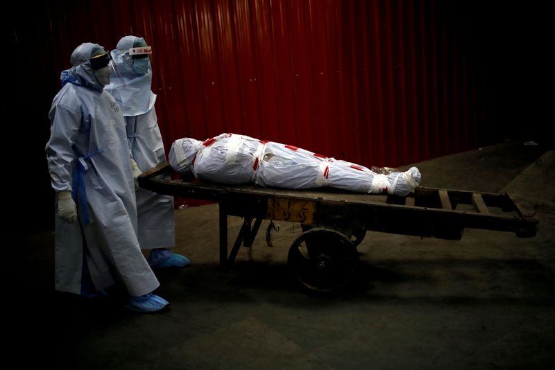 &copy; Reuters. FILE PHOTO: Health workers carry the body of a man who died due to the coronavirus disease in New Delhi