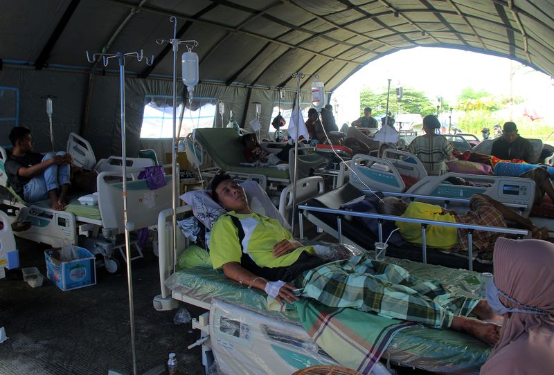 © Reuters. Injured people are treated at temporary shelter outside hospital following earthquake in Mamuju
